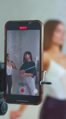 İki genç kız telefonda belin ölçüsünü alırken bir video kaydediyor.