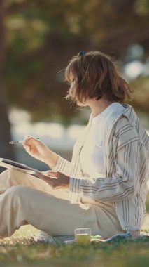 İki kadın arkadaş parkta resim çizerek ve konuşarak vakit geçiriyorlar. Orta çekim