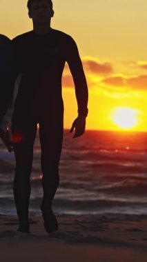 Gün batımında ilerleyen dalgıç kıyafetli bir adamın silüeti. Orta çekim