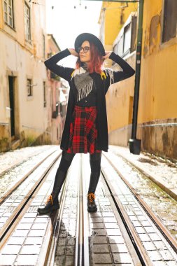 Tramvay rayları olan bir sokakta poz veren trend bir kadın, Avrupa mimarisini keşfediyor
