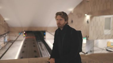 Trenin gelmesini beklerken metroda tek başına oturan düşünceli genç adam.