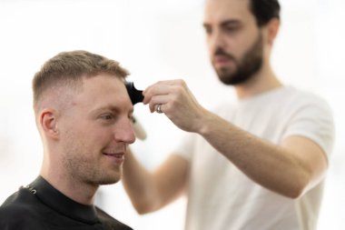 Bir kuafördeki yetenekli bir berberden profesyonel saç kesimi hizmeti alan bir müşteri.