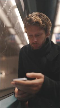 Yakışıklı bir adam gece trenle gidip geliyor, cep telefonuyla mesaj atıyor ve gülümsüyor.