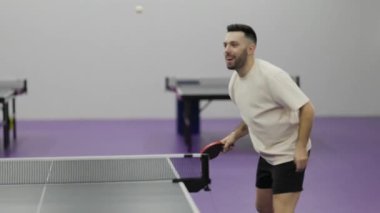 Mutlu genç adam dostça bir masa tenisi maçında sayı atarak zaferi kutluyor.