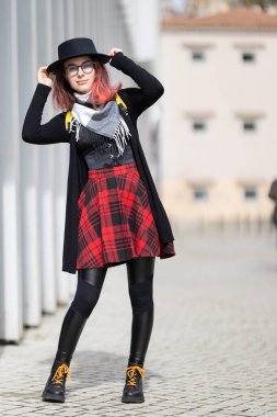 Şehir sokaklarında poz veren şık genç bir kadın, bireyselliğini ve modasını ifade ediyor.