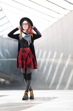 Ayakta duran, modern tarz ve bireysellik saçan genç bir kadın.