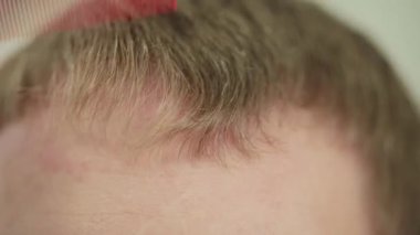 Sarı saçlarını tarayan ve saç kesimini şekillendiren birinin yakın çekimi.