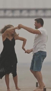 Rıhtımda dans eden, arka planda köprü olan romantik bir çift. Orta çekim