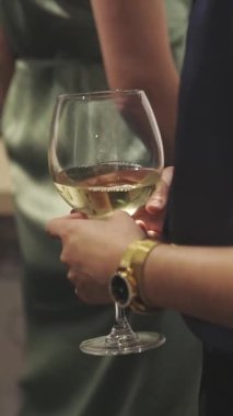 Koyu mavi bluzlu başarılı bir kadın etkinlikte elinde bir bardak beyaz şarap tutuyor. Orta çekim