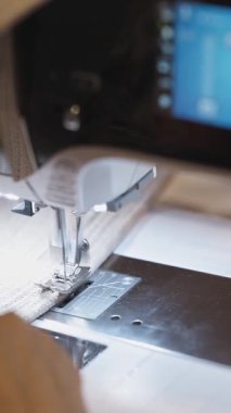 Bir kadın dikiş makinesi kullanarak fabrikada dikiş dikiyor. Orta çekim