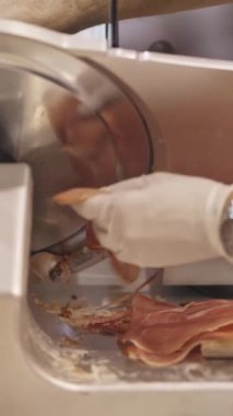 Jambon dilimleme makinesi kullanılarak parçalara ayrılıyor. Orta çekim