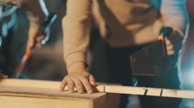 Gözlüklü genç, geceleri marangozluk atölyesinde tahta kesmeyi öğreniyor.