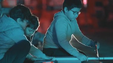 Kardeşler gece karanlık bir projede işbirliği yapıyor. Konsantrasyon ve takım çalışması ile ahşap bir kalas kesiyorlar.