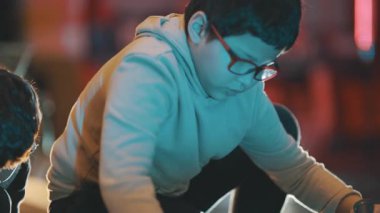 Gözlüklü genç gece bir atölyede odun keserken konsantre oluyor.