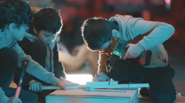 Bir atölyedeki marangozluk projesinde birlikte çalışan bir grup genç çocuk.