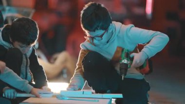 Genç öğrenciler marangozluk atölyesinde birlikte marangozluk eğitimi alıyorlar.