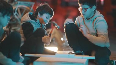 Hevesli çocuklar marangozluk projesinde işbirliği yapıyor, çivi çakıyor ve tahtayla çalışıyor.