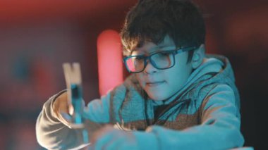 Gözlüklü, tahta çivi çakan, temel inşaat becerilerini öğrenen meraklı genç bir çocuk.