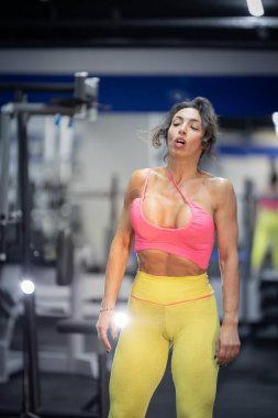 Yorgun, sporcu bir kadın spor salonunda yoğun bir spor yaparken nefes alıyor.
