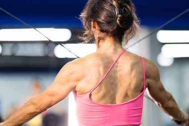 Kablo makinesi egzersizi sırasında sırt ve omuz kaslarına odaklanan kadın.