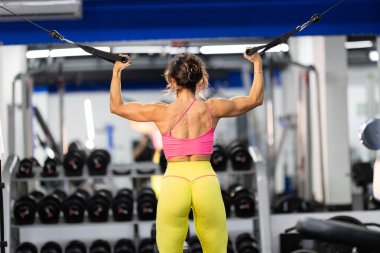 Atletik kadın kablo makinesiyle üst vücut egzersizi yaparak fiziksel güç kazanıyor.