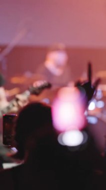 İnsanlar bir gece kulübündeki rock konserinde eğleniyor. Orta çekim