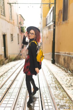 Tramvay raylarıyla Avrupa şehir caddesini keşfederken gülümseyen genç bir kadın