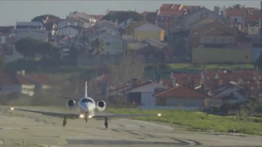 Arka planda bir şehir olan küçük bir özel uçak hızlanıyor ve kalkıyor.
