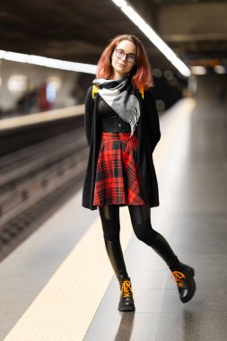 Metroda duran genç bir kadın, toplu taşıma için bekliyor, şehir içi ulaşım kavramı