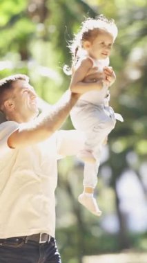 Parkta bir aile yürüyor - bir baba kızını kusuyor. Orta çekim