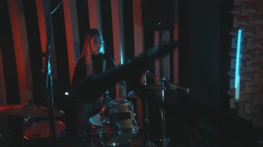 Genç bayan davulcu enerjiyle profesyonel bir kayıt stüdyosunda davul çalıyor.
