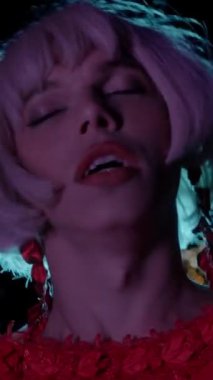 Kırmızı elbiseli travesti caddede neon ışıklı kamera önünde hava atıyor. Portre