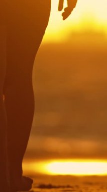 Gün batımında kıyıda yürüyen zarif genç bir kadının çıplak ayakları. Orta çekim