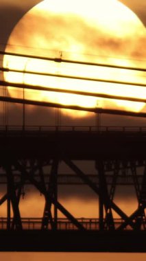 Köprüde araba trafiği ve gün batımında kara bulutlarla kaplı büyük parlak bir güneş. Orta çekim