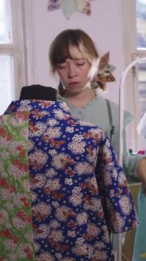 Bir kadın tasarımcı renkli giysileri bir mankenin üzerinde deniyor. Orta çekim