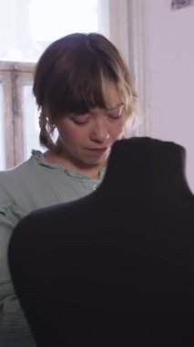 Bir kadın renkli tasarımcı kıyafetlerini bir mankenin üzerinde deniyor. Orta çekim