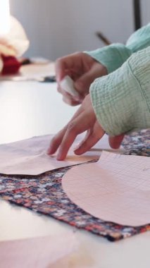 Kadın tasarımcı, çiçek kumaşında kağıt desenler kullanarak işaretler yapıyor. Orta çekim