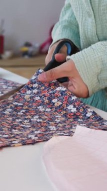 Kadın tasarımcı, çiçek kumaşından makas desenleri kullanıyor. Orta çekim