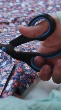 Çiçek kumaşındaki desenleri makas kullanarak kesiyor. Orta çekim