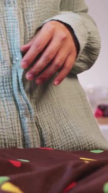 Bir kadın elbiseye ütü masasına su püskürtür ve ütülemeye devam eder. Orta çekim