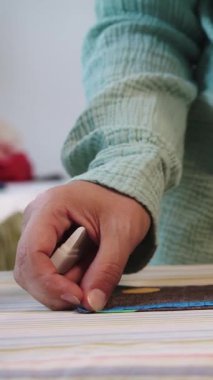 Bir kadın ütü masasında küçük bir kumaş parçasını bir metreyle ölçer. Orta çekim