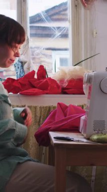 Terzi işyerine oturur ve kırmızı giysiler dikmeye başlar. Orta çekim