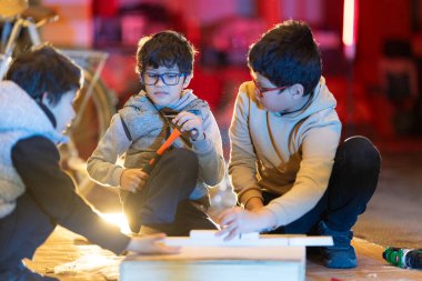 Yaratıcı bir atölye ortamında çocuklar marangozluk projesinde birlikte çalışıyorlar.