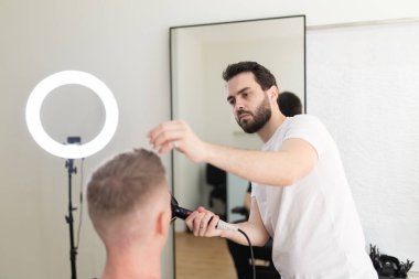 Parlak bir kuaförde erkek müşteriye modern bir saç kesimi sağlayan profesyonel berber.