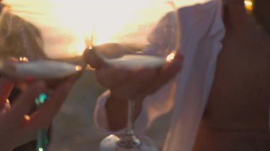 Sahilde gün batımında kırmızı şarabı iki bardağa dolduran elleri kapatın.