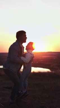 Adam oğluyla oynuyor - gökyüzüne kusuyor - aile gün batımında, manzara arka planda