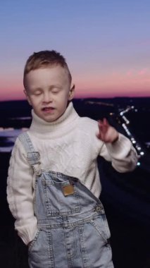 Gün batımının önünde elinde şarap kadehi tutan genç bir çocuk.