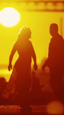 Siluetli çift bir anı paylaşıyor. Gün batımında ya da gün doğumunda dans ediyorlar ve sarılıyorlar. Batan güneş ve ikonik köprü ortamı hazırlıyor..