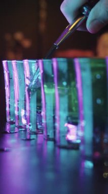 Bir sıra bardağa içki dolduran biri.