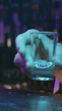 Barın önünde bardak tutan biri.